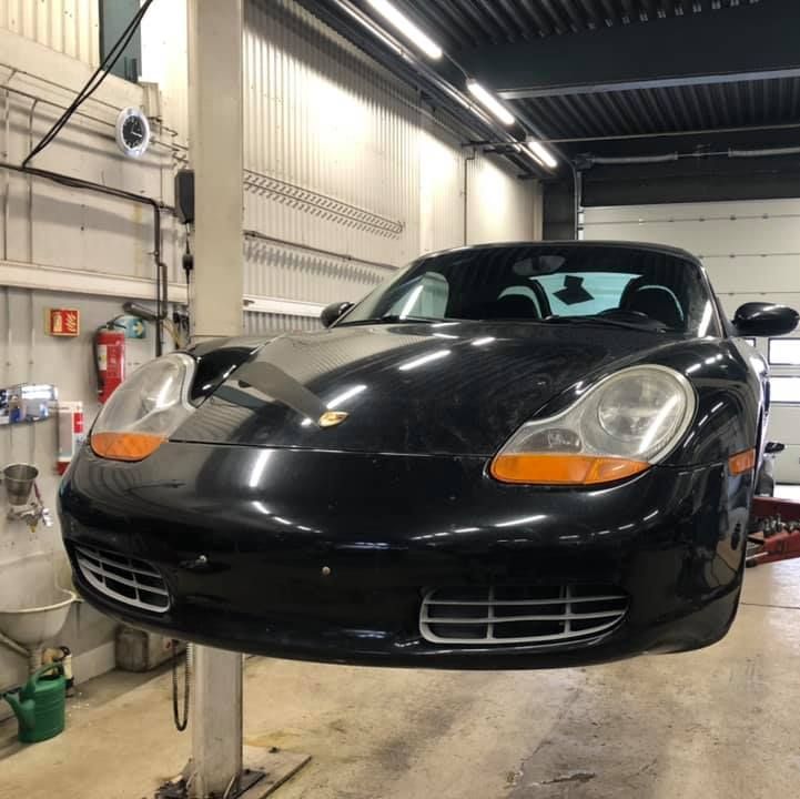 Svart bil heiset opp på verksted